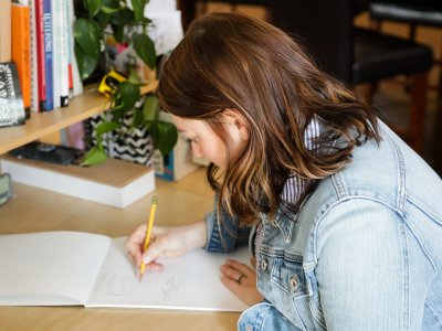 Girl drawing with pencil at her desk