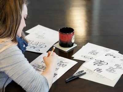Woman drawing at a table with a coffee mug